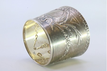 Argola de guardanapo em prata em forma de punho relevada com motivos florais envolvendo cartela para monograma.